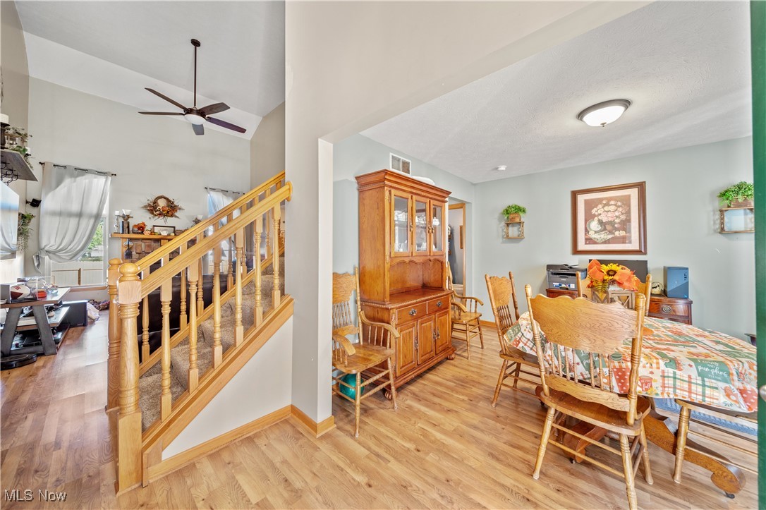 Dining room with high vaulted ceiling, light wood-type flooring, and ceiling fan