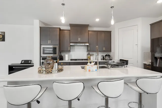 a kitchen with stainless steel appliances granite countertop a sink a stove a kitchen island with chairs and cabinets