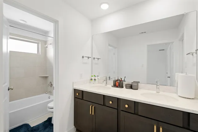 a bathroom with a tub sink double vanity and a mirror