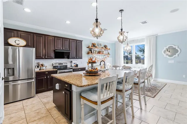 a kitchen with stainless steel appliances granite countertop a stove a refrigerator a oven a sink a dining table and chairs with wooden floor