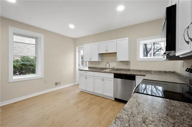 a kitchen with granite countertop a stove top oven sink and cabinets