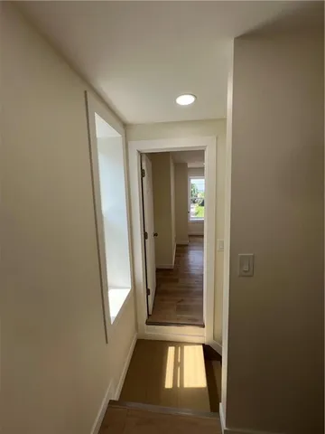 a view of a hallway with wooden floor and a living room