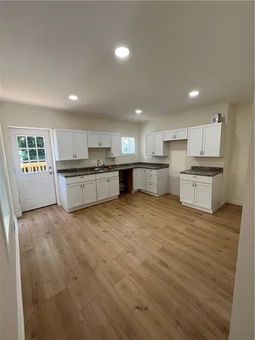 a large kitchen with stainless steel appliances granite countertop a stove a sink dishwasher and a refrigerator with wooden floor