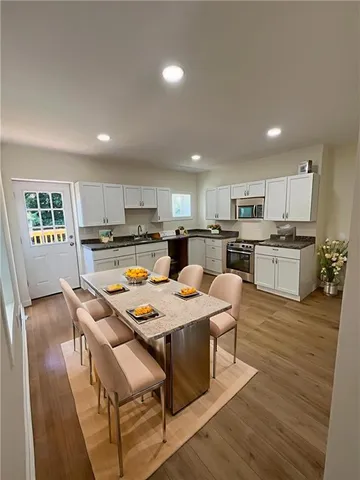 a kitchen with stainless steel appliances granite countertop a stove top oven a refrigerator a sink and a dining table with wooden floor