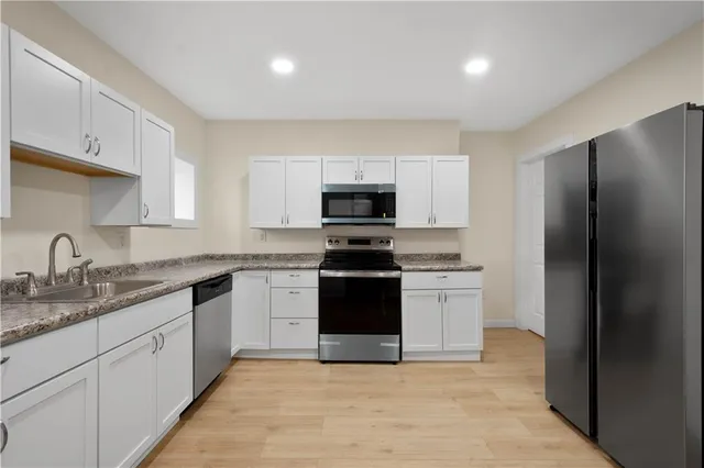 a kitchen with granite countertop white cabinets and stainless steel appliances