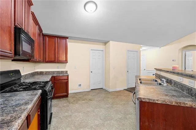 a kitchen with granite countertop a sink stove and cabinets