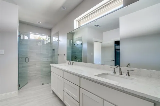 a bathroom with a double vanity sink mirror and shower