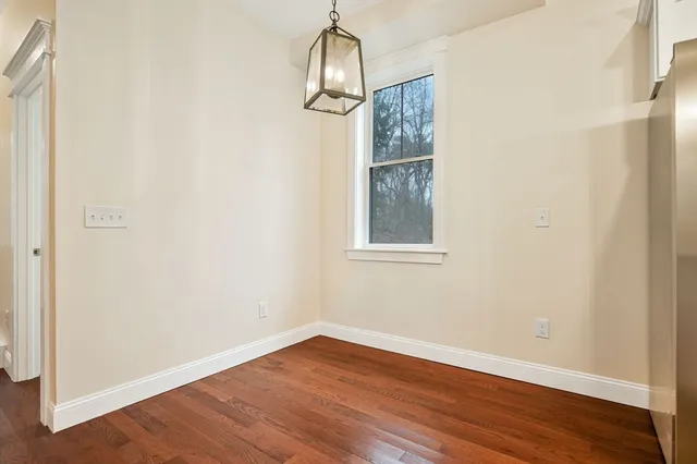 an empty room with wooden floor windows and entrance