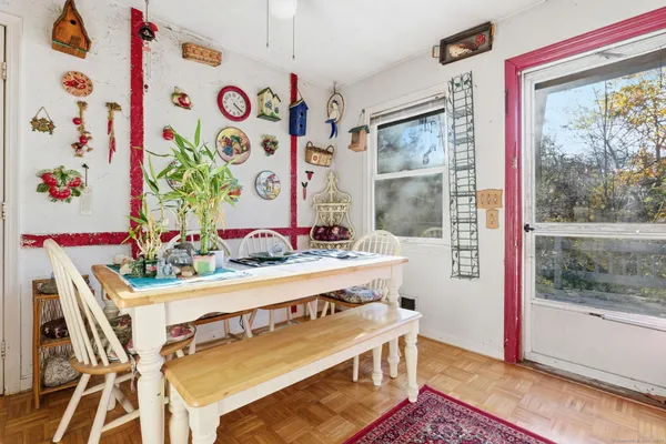 a view of a dining room with furniture a rug and a painting on the wall