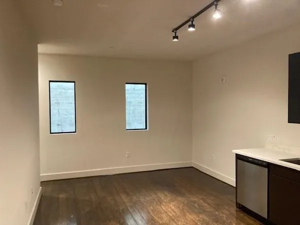 an empty room with wooden floor and windows