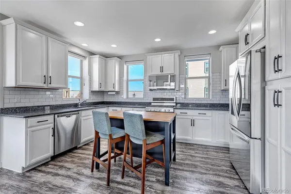 a kitchen with stainless steel appliances granite countertop white cabinets a sink and dishwasher