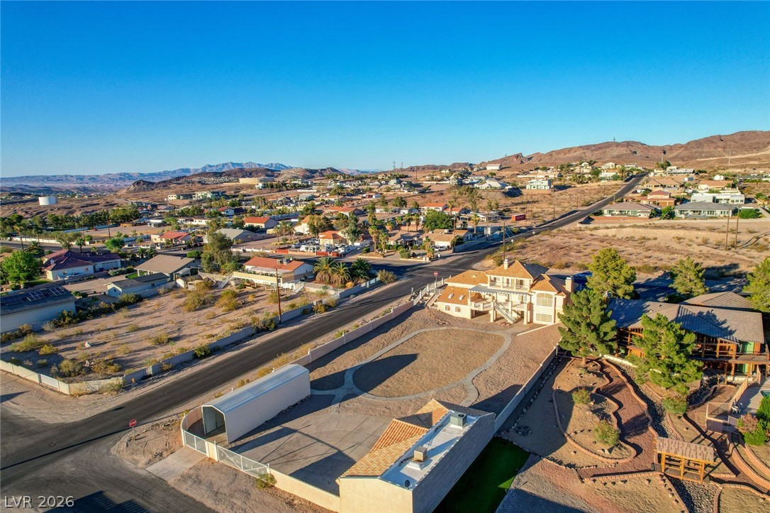 640 North Racetrack Road Henderson, NV 89015 - Photo 17 of 65 An aerial panorama reveals a vast desert community cradled by rugged mountains, with a prominent two-story residence.
