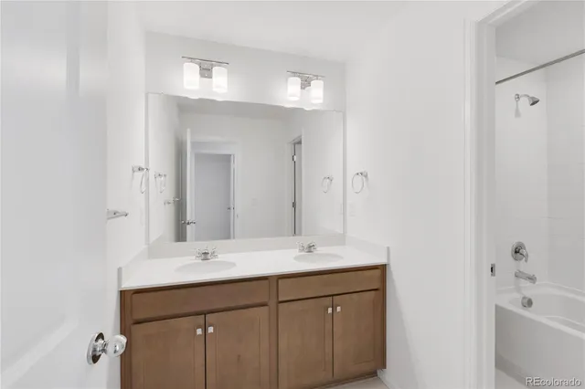 a bathroom with a double vanity sink mirror and bathtub