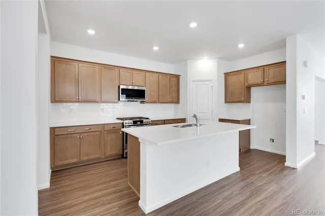 a kitchen with stainless steel appliances a sink stove and wooden floor