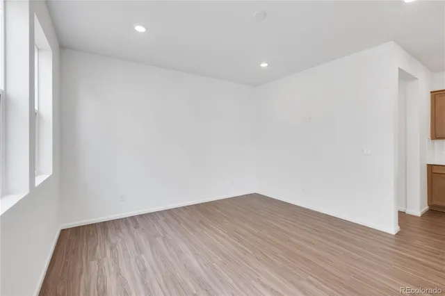 an empty room with wooden floor and windows