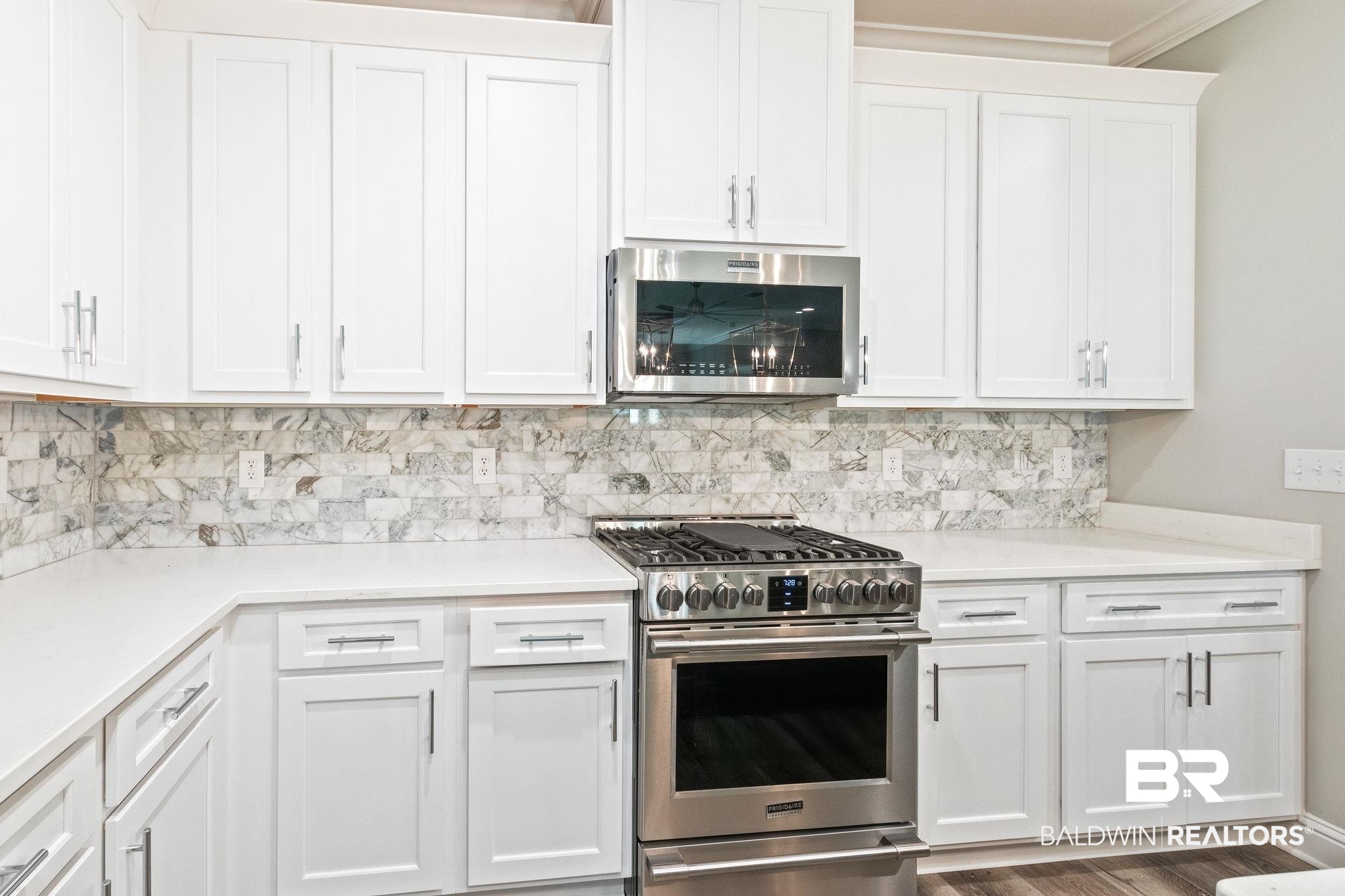 12441 Reunion Place Foley, AL 36535 - Photo 12 of 31 Kitchen featuring white cabinets, backsplash, stainless steel appliances, and hardwood / wood-style floors