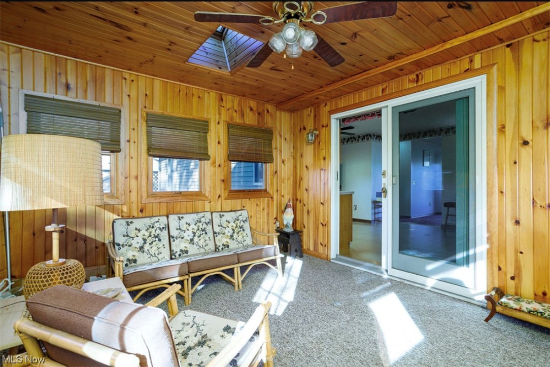 9066 Crow Road Litchfield, OH 44253 - Photo 19 of 28 Living room featuring wood walls, carpet, ceiling fan, and wood ceiling with skylights.