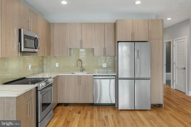 a kitchen with stainless steel appliances granite countertop a refrigerator a sink and a stove