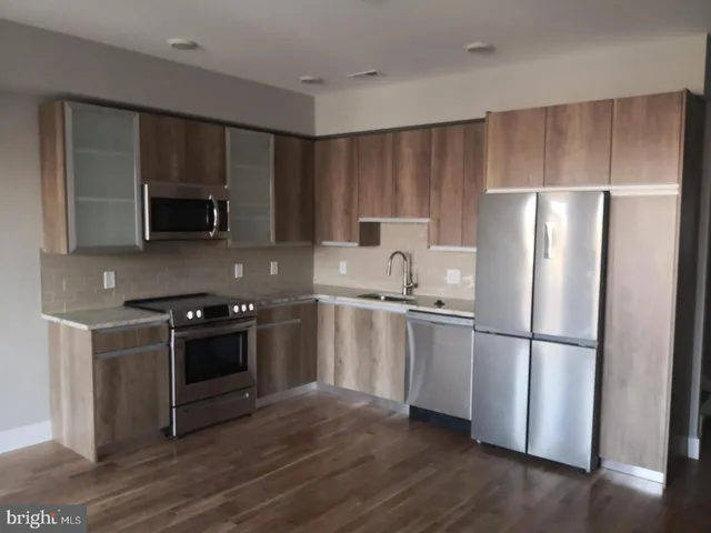 a kitchen with a refrigerator stove and wooden cabinets