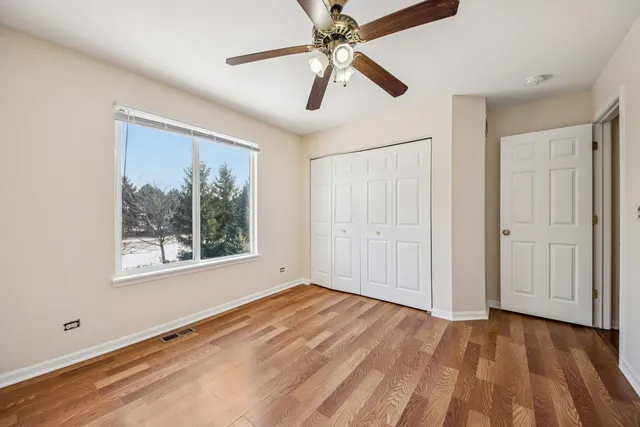 a view of empty room with wooden floor and fan