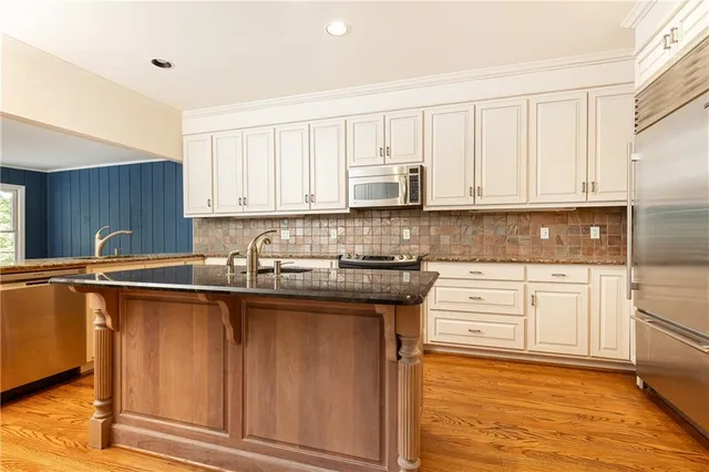 a kitchen with stainless steel appliances granite countertop a sink a stove and cabinets