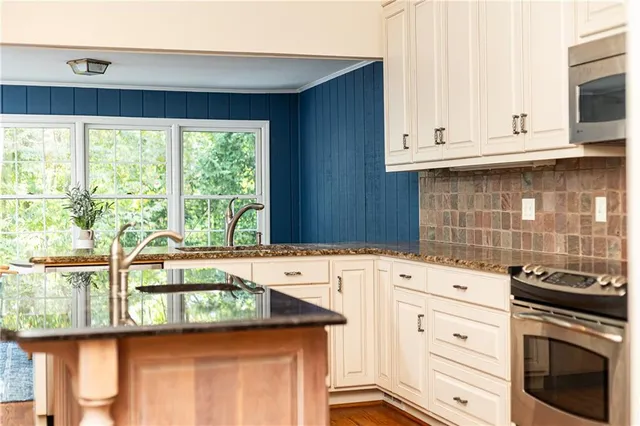 a kitchen with granite countertop white cabinets and window