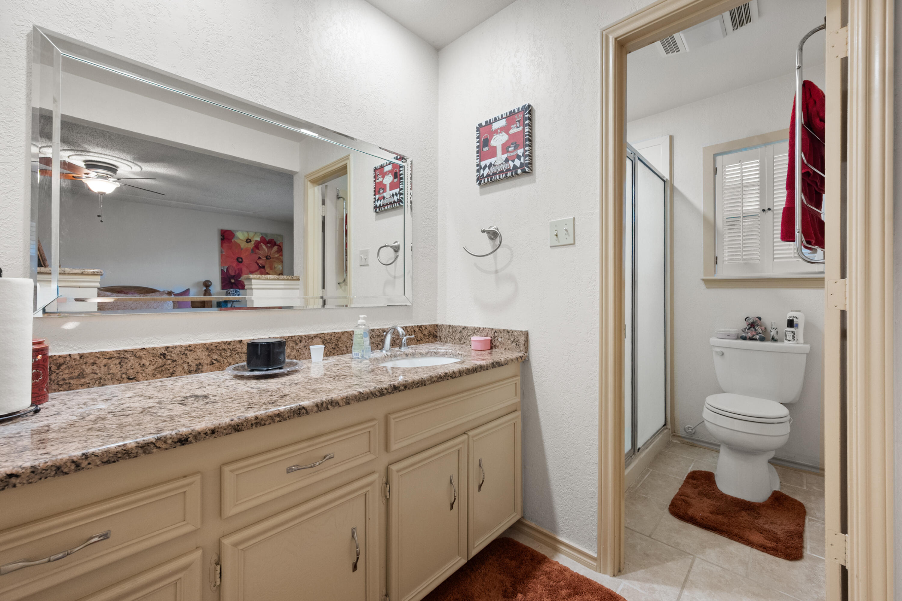 4610 63rd Street Lubbock, TX 79414 - Photo 23 of 30 a bathroom with a granite countertop sink a toilet and a mirror