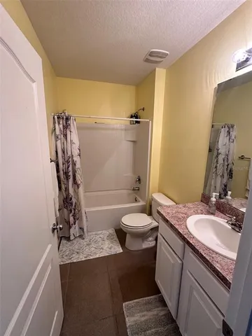 a bathroom with a granite countertop sink a toilet and shower