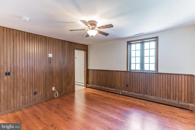 an empty room with wooden floor chandelier fan and windows