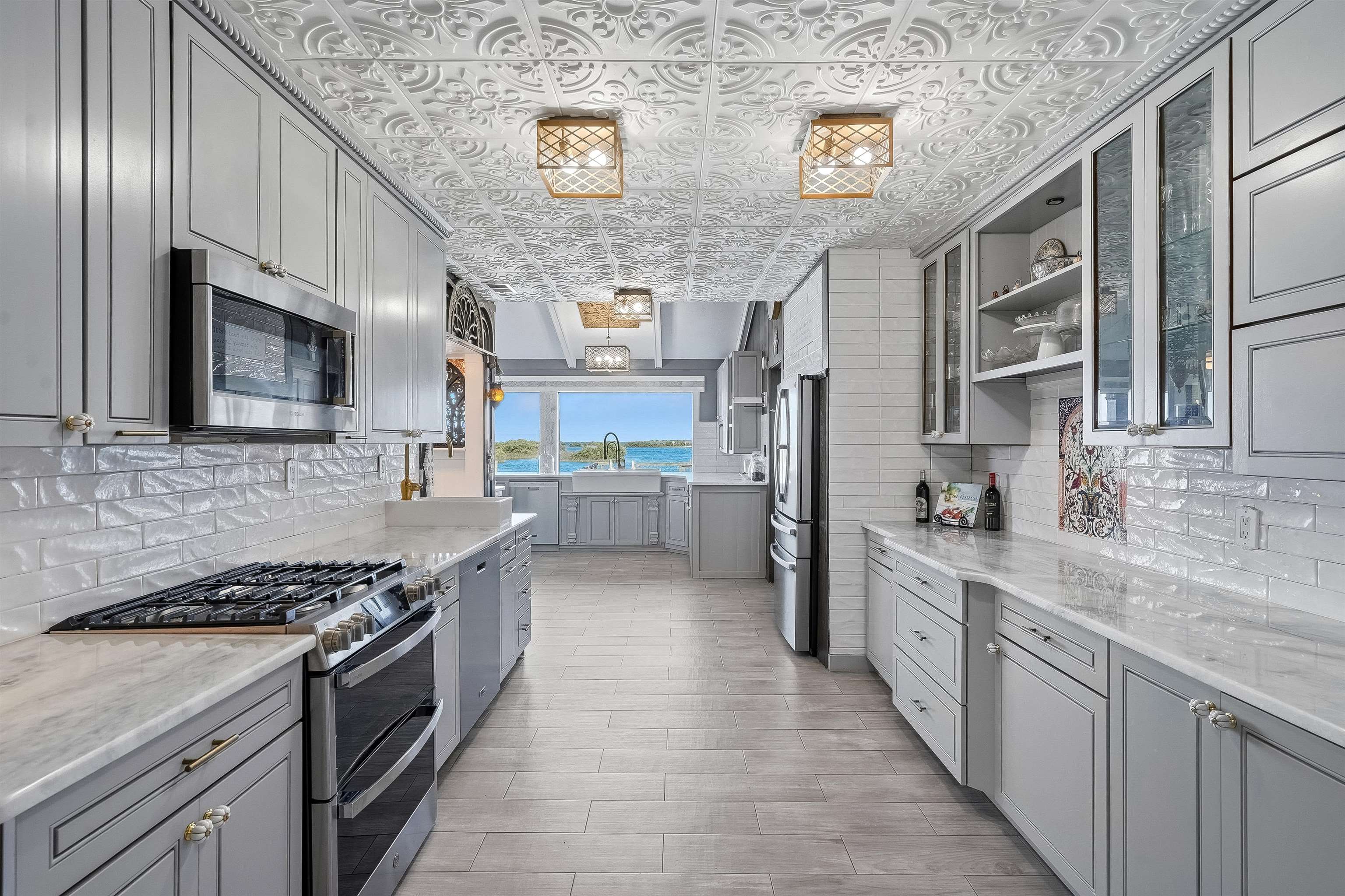 71 Water Street St. Augustine, FL 32084 - Photo 16 of 58 Kitchen featuring gray cabinetry, stainless steel appliances, glass fronted cabinets, and an ornate ceiling.