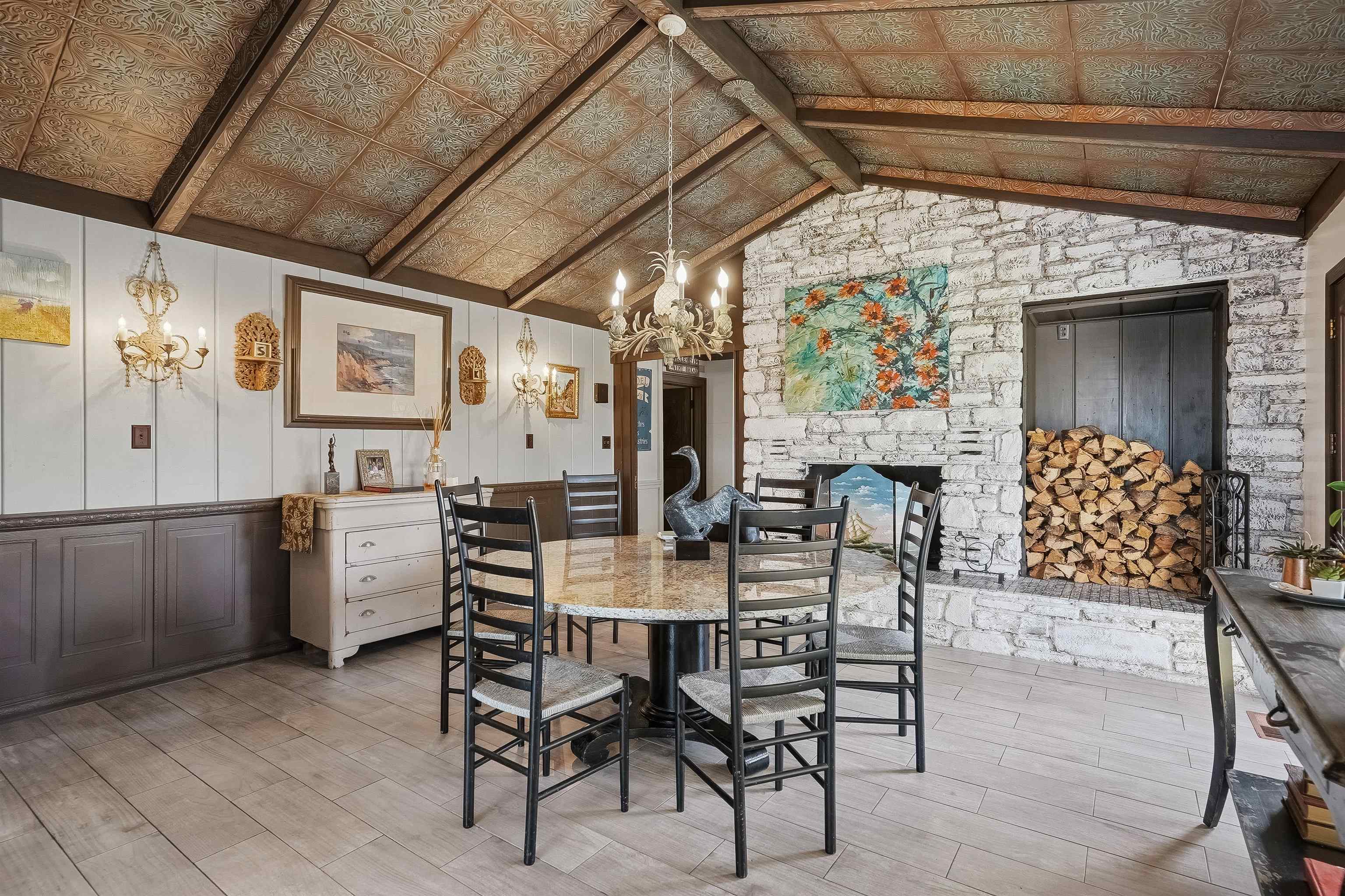 71 Water Street St. Augustine, FL 32084 - Photo 2 of 57 Dining space featuring a decorative wall, a chandelier, wood finish floors, beamed ceiling, and a stone wood burning fireplace.