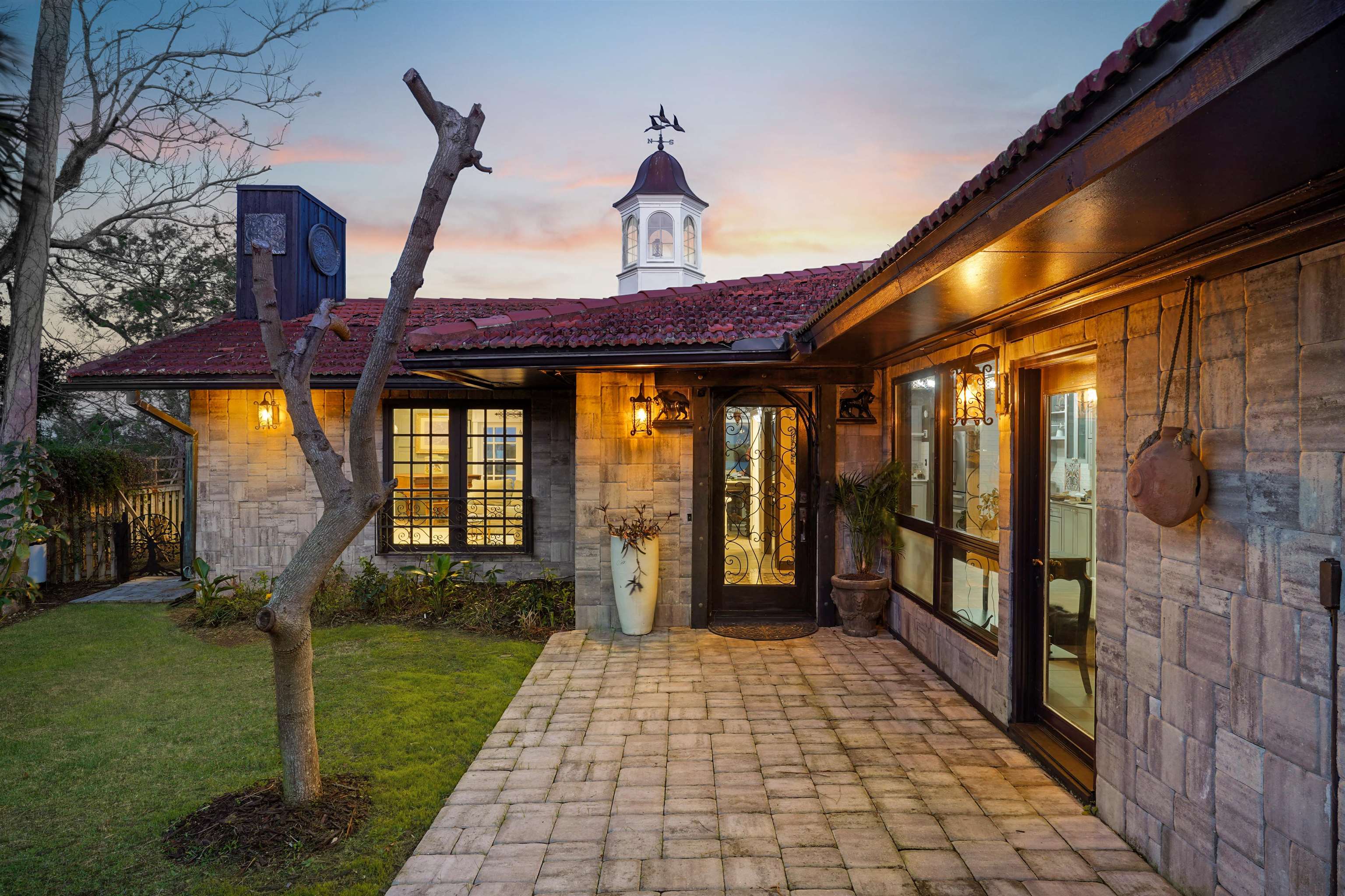 71 Water Street St. Augustine, FL 32084 - Photo 4 of 58 Exterior entry at dusk with a yard, stone siding, and a patio