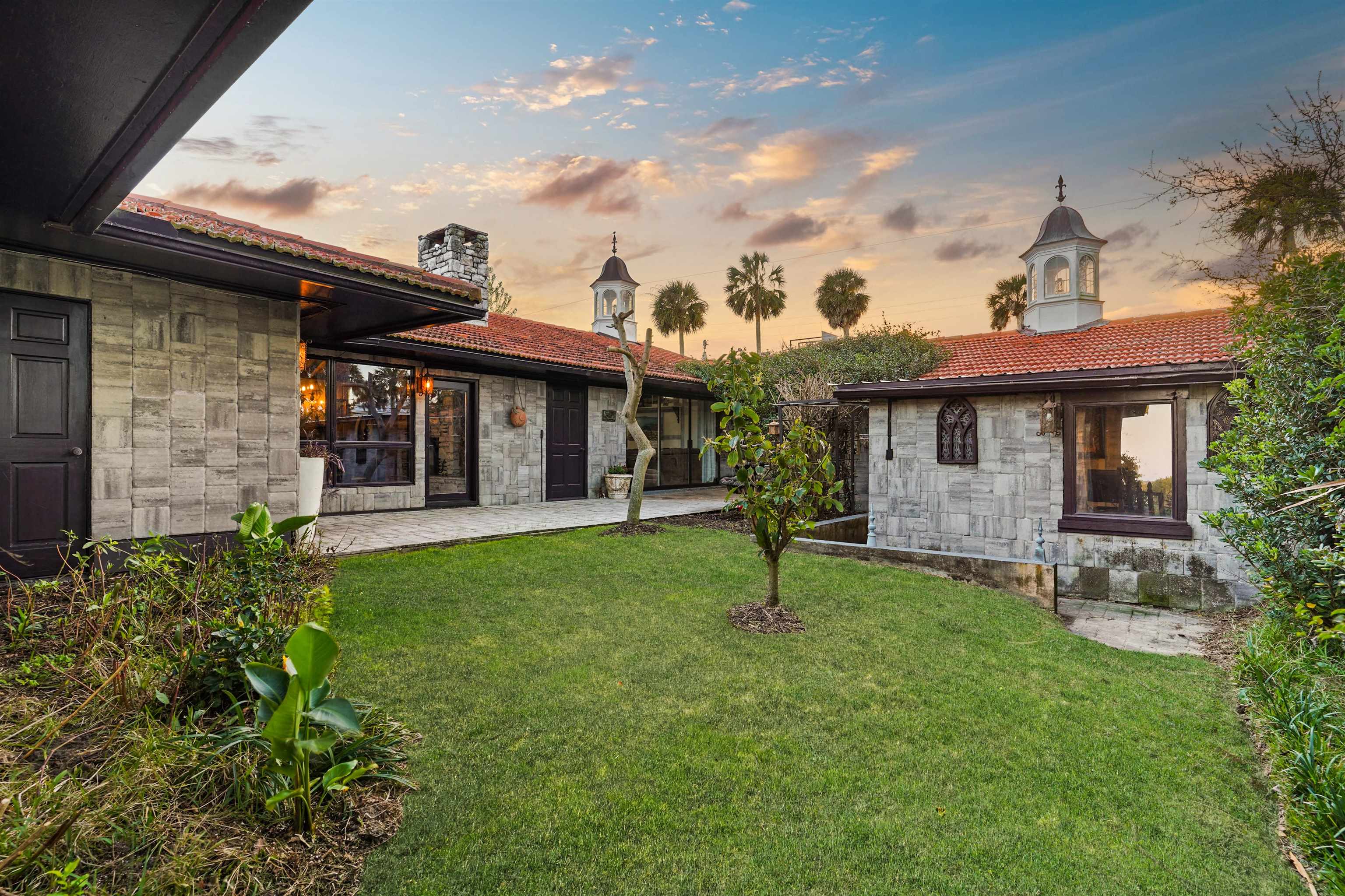 71 Water Street St. Augustine, FL 32084 - Photo 43 of 58 Back of house at dusk featuring stone siding and a yard