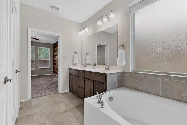 a bathroom with a tub sink and mirror