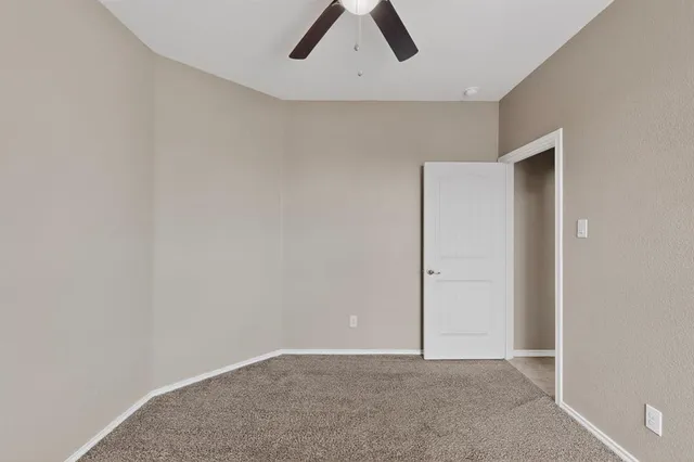 an empty room with ceiling fan and window