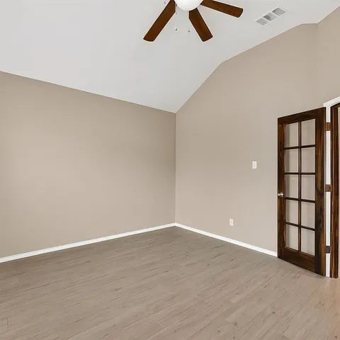 an empty room with windows and ceiling fan