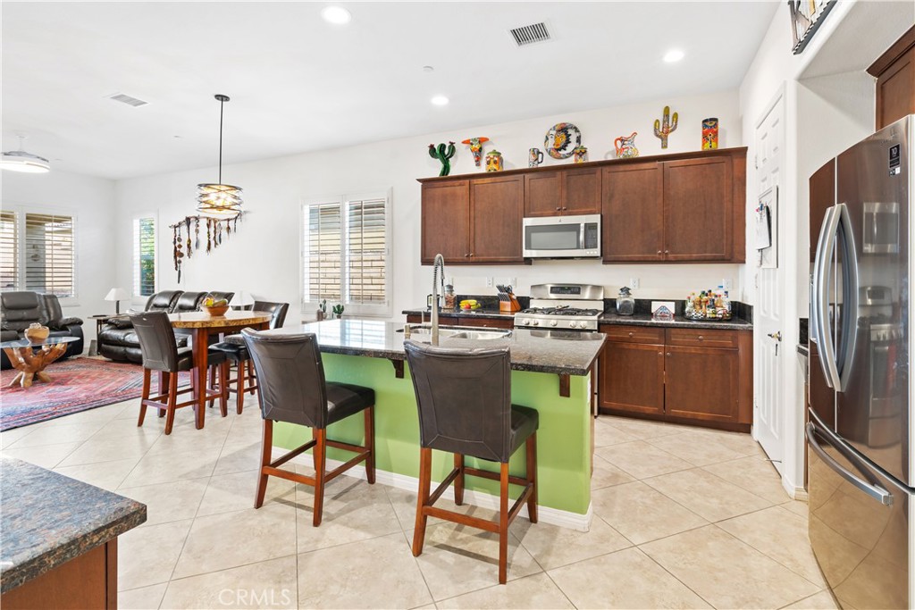 a kitchen with stainless steel appliances granite countertop a refrigerator a stove a sink a dining table and chairs