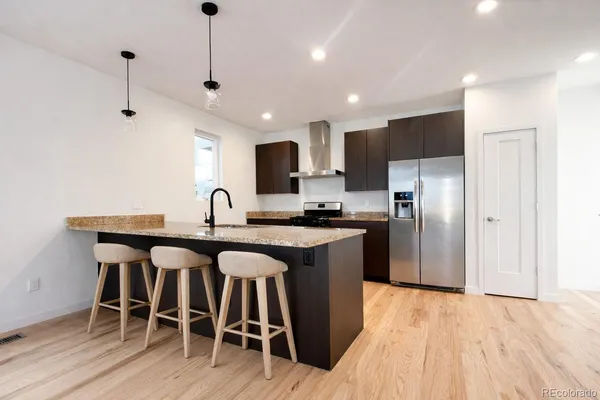 a kitchen with stainless steel appliances granite countertop a table chairs refrigerator and microwave