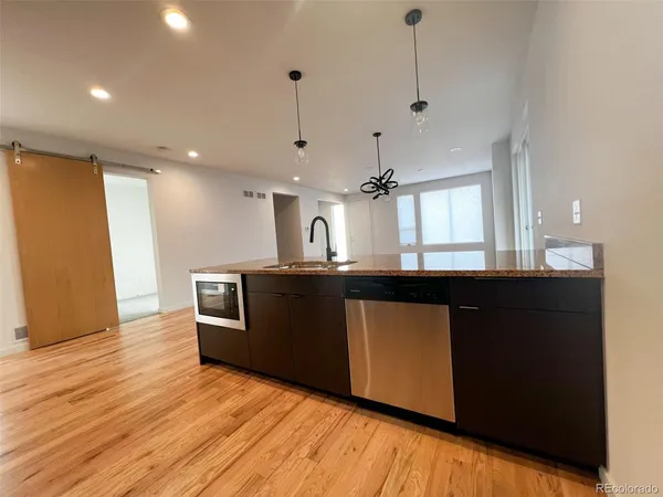 a kitchen with kitchen island wooden floors granite counter tops and a view of living room