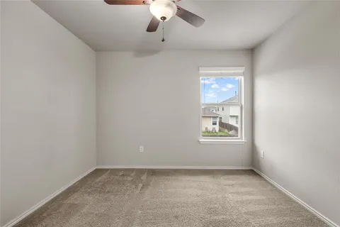 an empty room with a window and a ceiling fan
