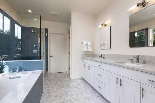 a bathroom with a granite countertop double vanity sink a mirror and a bathtub