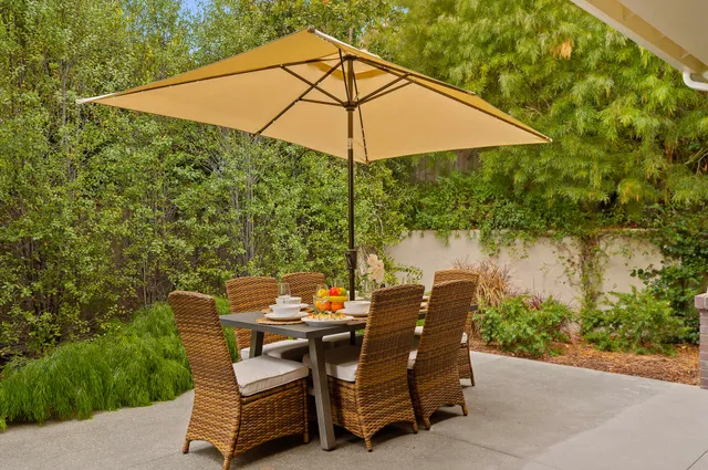 a backyard of a house with table and chairs under an umbrella