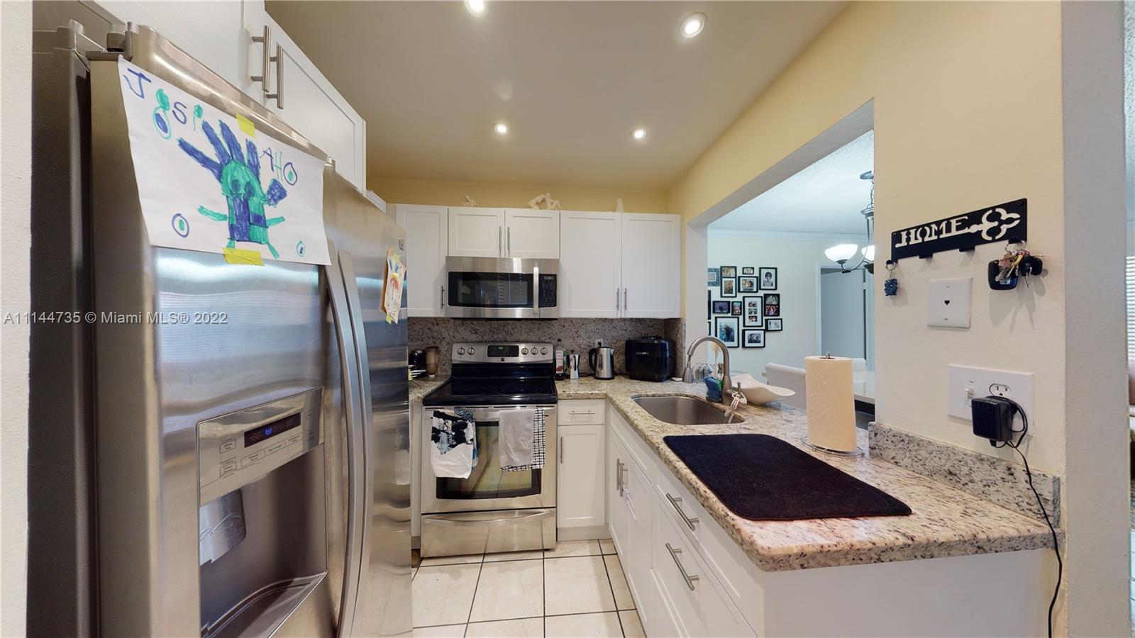 14911 Southwest 104th Street, Unit 1722 Miami, FL 33196 - Photo 15 of 29 a kitchen with stainless steel appliances kitchen island granite countertop a refrigerator and a stove top oven