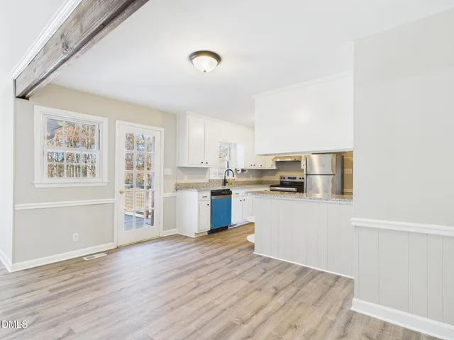a kitchen with stainless steel appliances wooden floor and a window