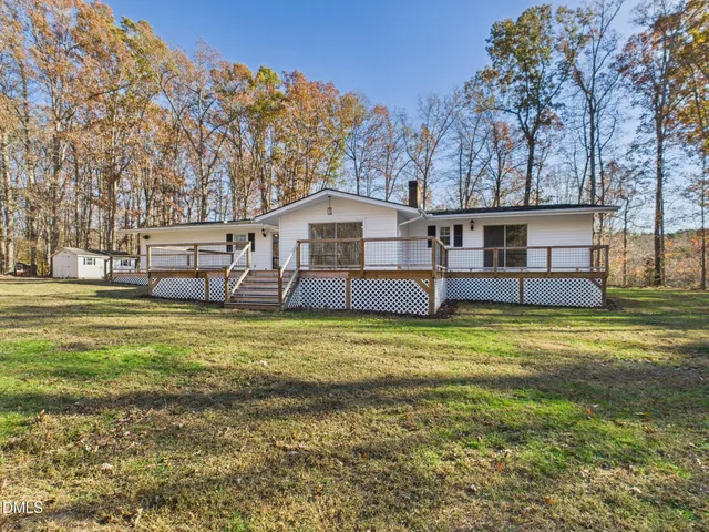 a view of a house with a big yard and large tree