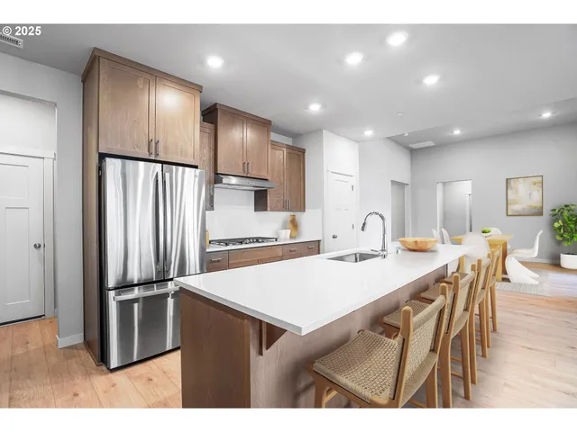 a kitchen with stainless steel appliances refrigerator dining table and chairs