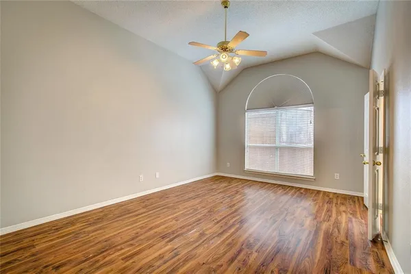 an empty room with wooden floor chandelier and windows