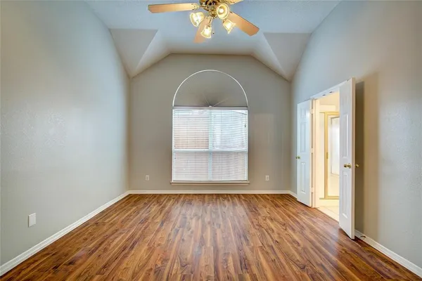 an empty room with wooden floor fan and windows