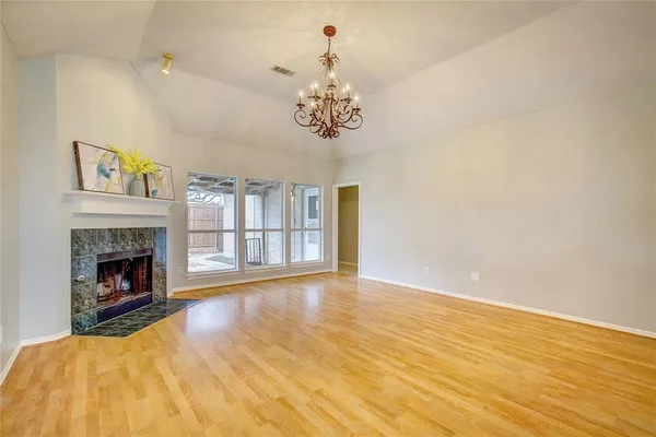 a view of an empty room with chandelier and wooden floor