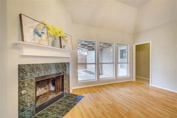 a view of an empty room with wooden floor fireplace and a window